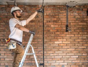 Electrician working on cables in a construction building. If you need to do a pre-purchase electrical inspection, contact Allyn White now!