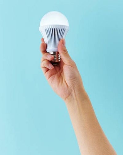 A hand holding an LED light bulb. If you need help with LED lightning and installation in Alderley, Ashgrove, Paddington, and Bardon, contact Allyn White Electrical now!